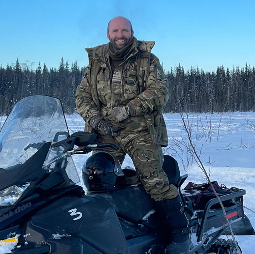 Red Team Drones expert Jonathan Lowe riding a snowmobile in camouflage uniform during Arctic operations in the High North.
